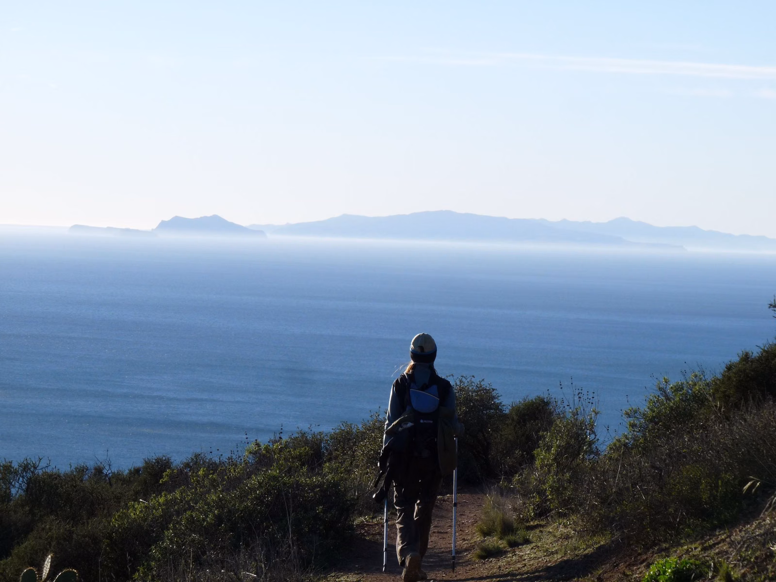 Hiker on a coastal trail above the Pacific with Anacapa and Santa Cruz islands on the horizon