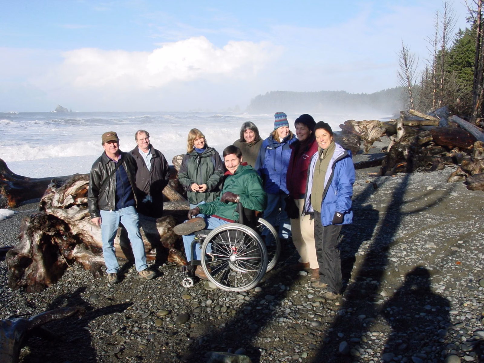 Group of visitors with a beach wheelchair on the shore