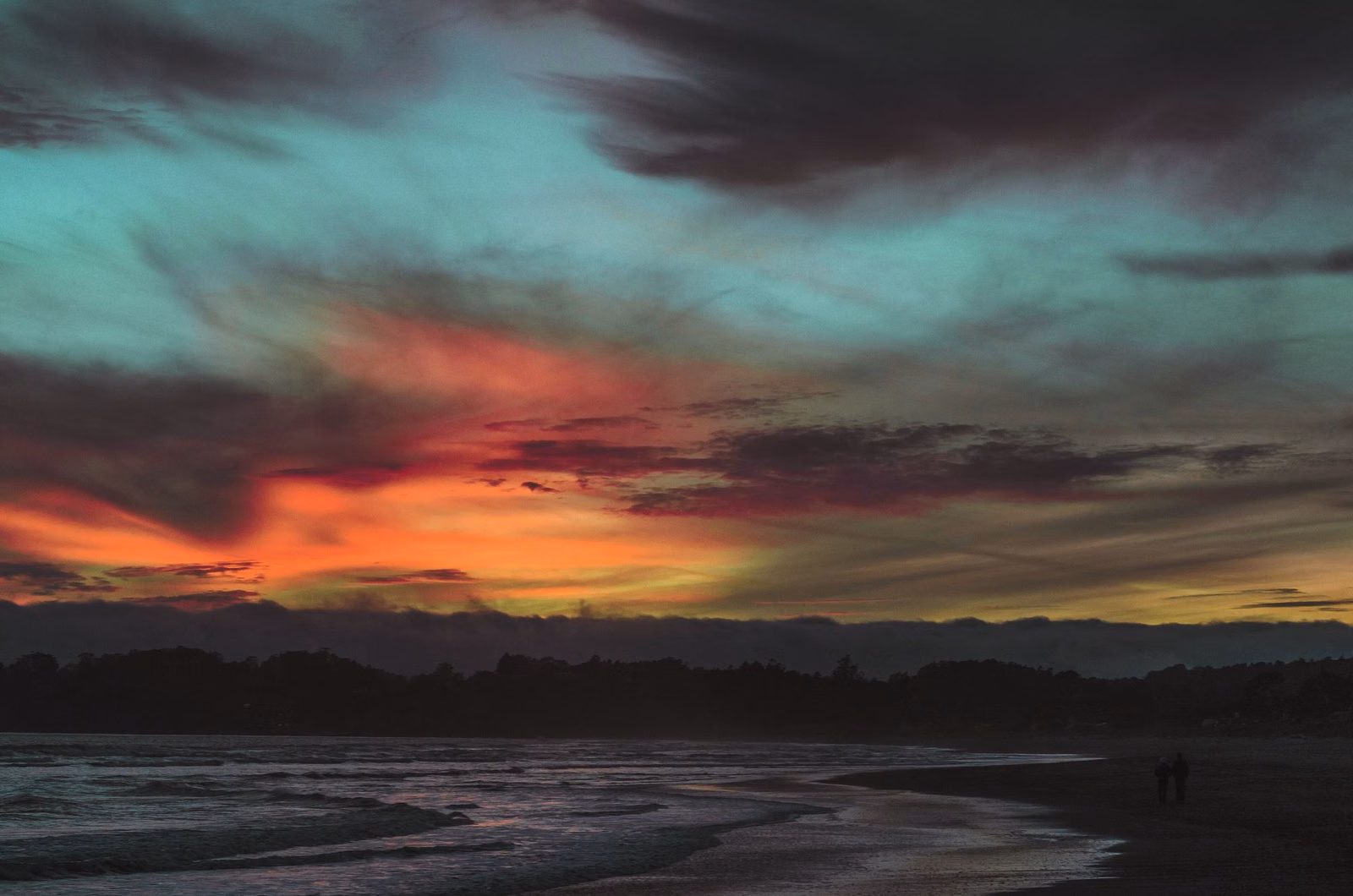 Red and orange sunset clouds over a quiet beach at dusk