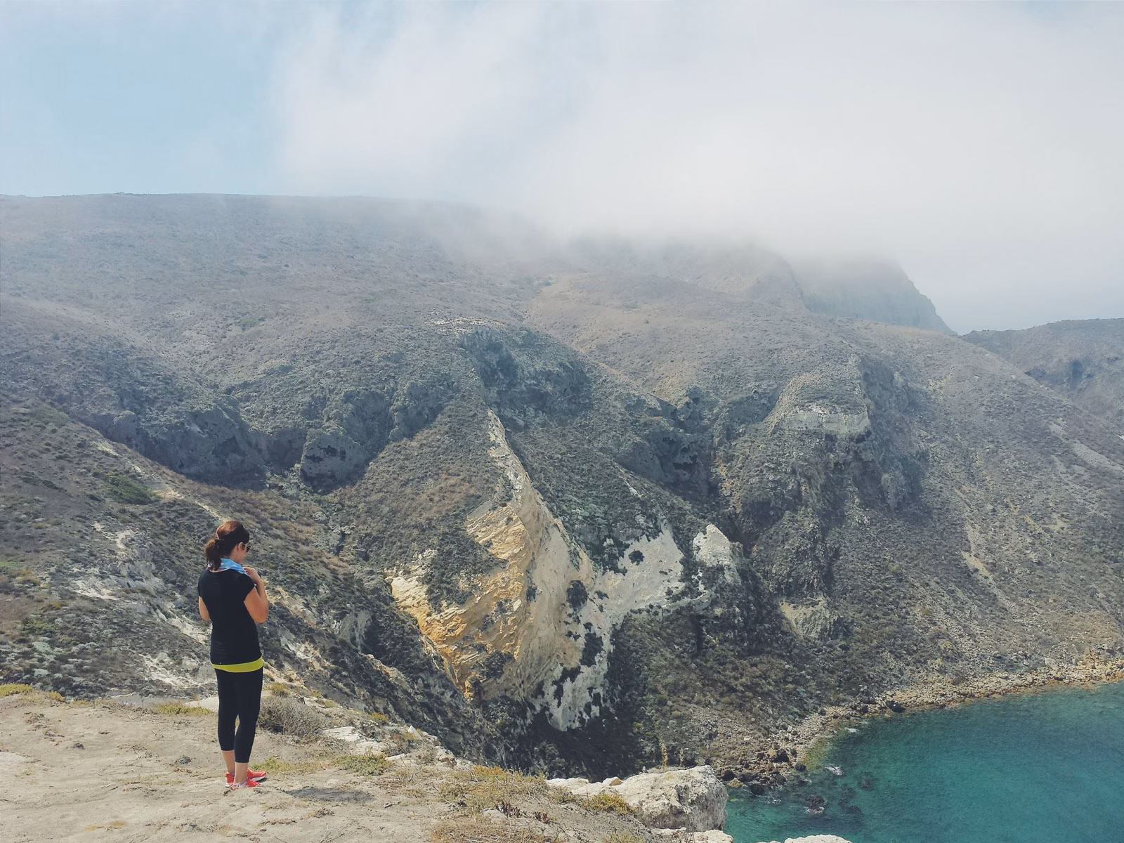 Visitor looking out over steep coastal cliffs and the sea