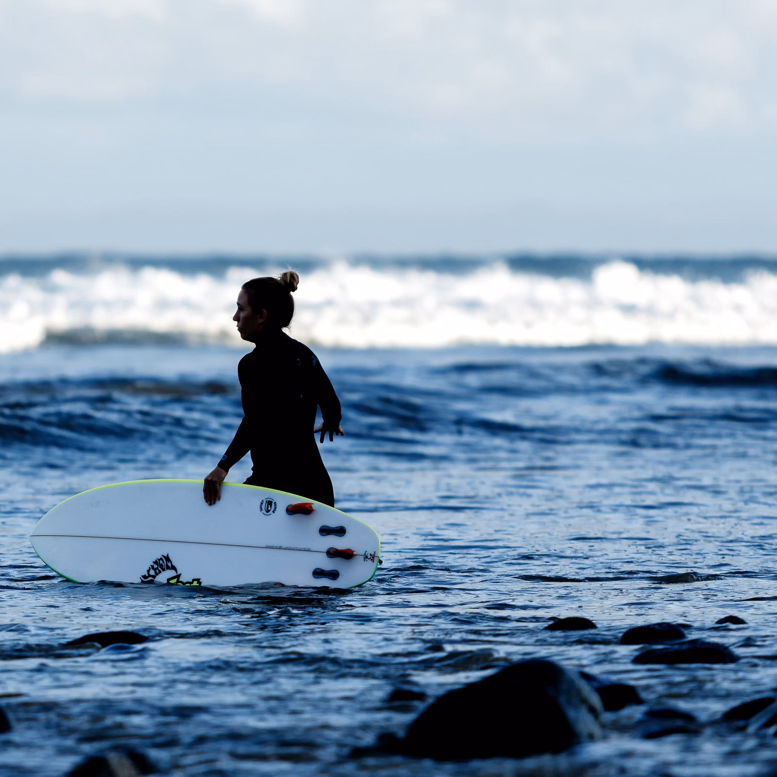 Surfer carrying a board into small surf